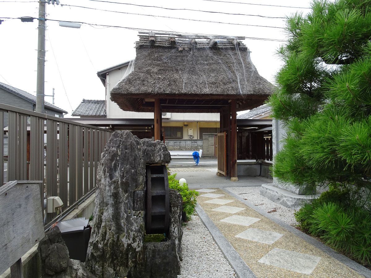 Die Rückseite des Tors des Koizuka-dera Tempels mit einem Wasserrad im Vordergrund